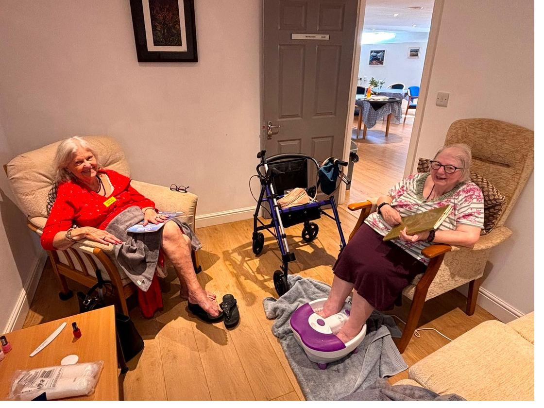 A member of staff sitting with a lady, doing her nails and chatting